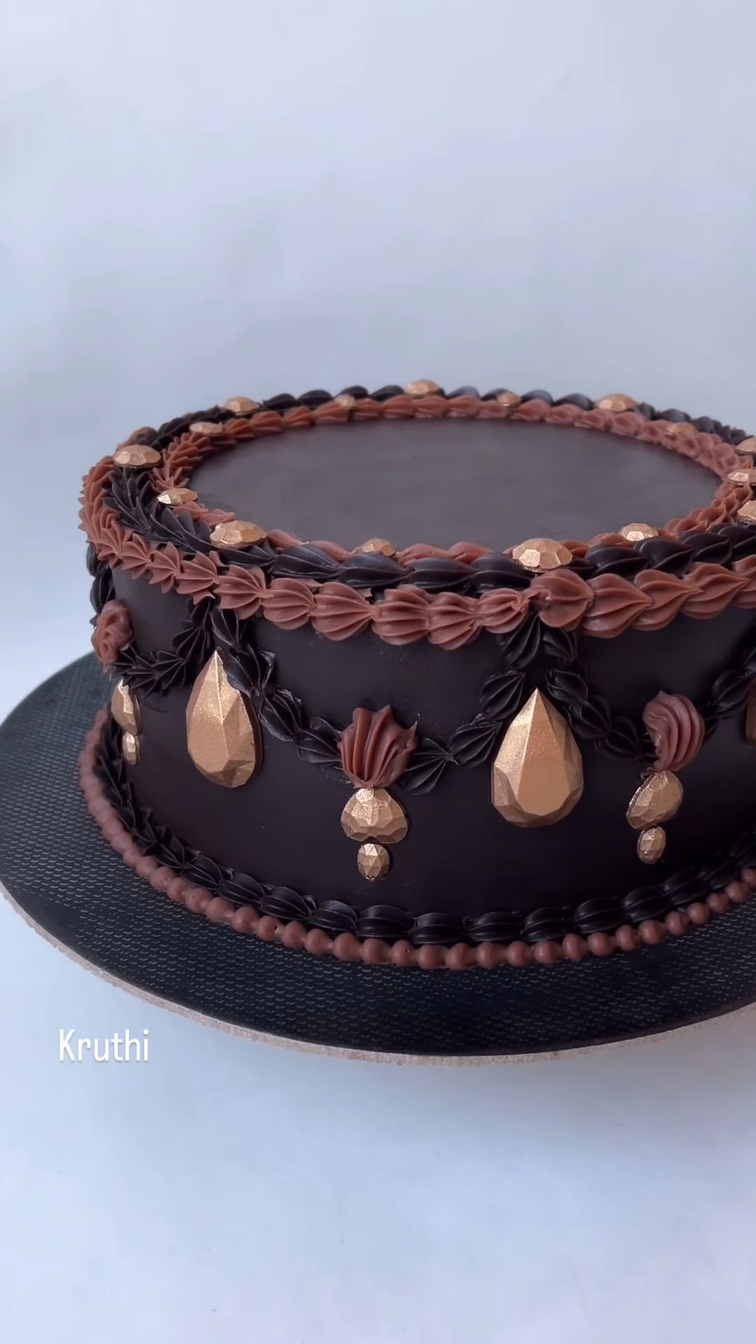 Dark chocolate cake with ornate piped border and gold details